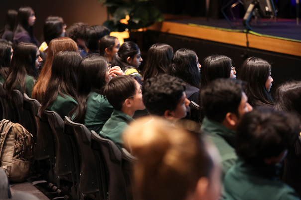 Students sitting in an auditorium listening to a speaker.  