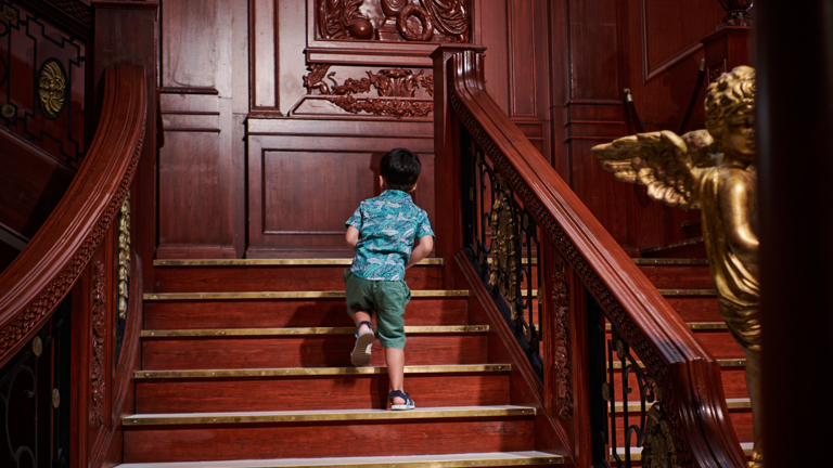 A small boy walking up the Grand Staircase in Titanic: The Artefact Exhibition