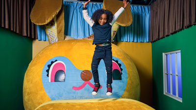  a young child jumps up in joy atop a giant stuffed bunny. 