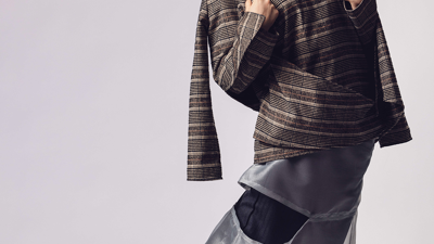 Person wears a brown tweed oversized top with sheer grey wide-leg trousers and black heels.