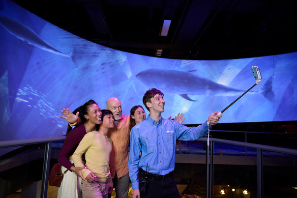 A tour guide using a selfie stick with a family touring Our Wondrous Planet exhibition at Melbourne Museum.