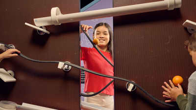 Children having fun designing their own roller-coaster for balls using different parts on a peg-wall.