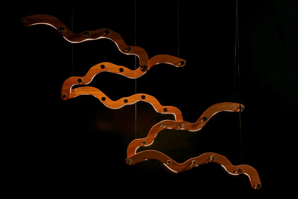 Suspended light feature with sculptural, undulating wood components.
