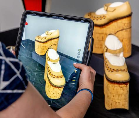A person uses an iPad to photograph shoes in the Learning Lab at Melbourne Museum during a Digital Art Class.