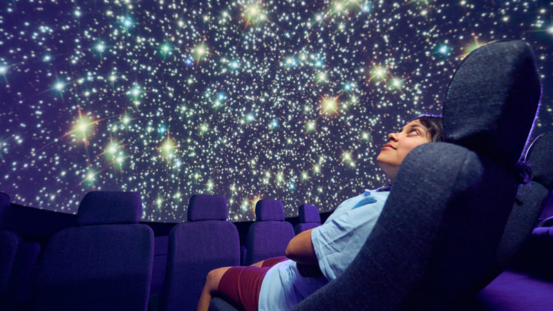 A secondary school student observes a projection of the stars on the dome of the Melbourne Planetarium 