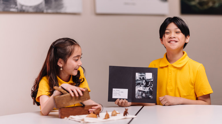 A girl and boy laughing and looking at museum objects.