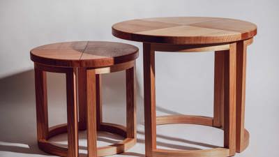 A pair of wooden nesting tables with segmented, circular tops and curved legs in contrasting light and dark timber tones.
