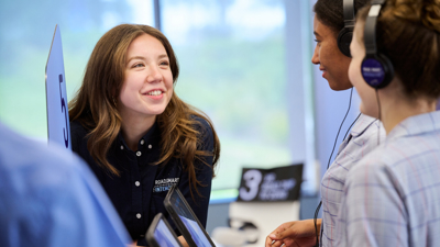 A learning facilitator talks to two students wearing headphones as part of Road Smart Interactive 