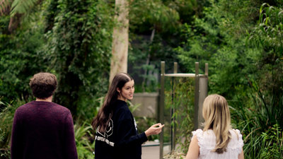 Three people walking away from the camera in the Forest Gallery at Melbourne Museum.