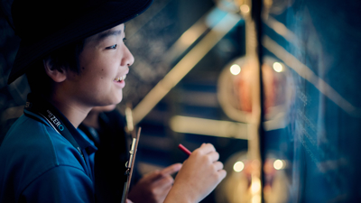 A student standing in front of a touch screen in the Road to Zero Experience Space 
