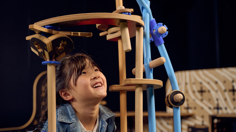 A child developing STEM skills by engineering a structure out of loose parts in Tinkertown exhibition at Scienceworks.
