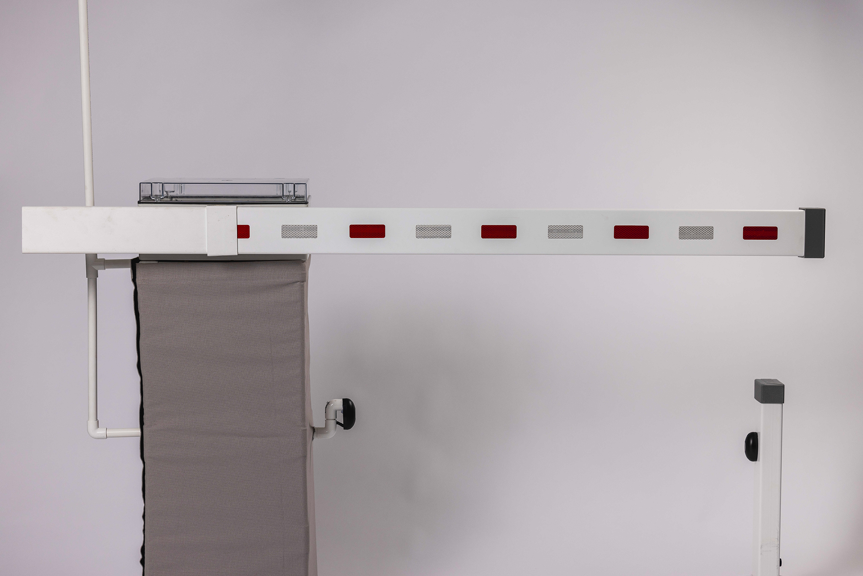 Automated boom gate with a white barrier arm featuring red and reflective markings.