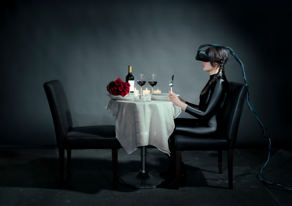 Young woman wearing an AR headset and black catsuit sits at a table set for a romantic dinner, with roses and lit candles.