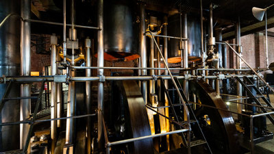 Large steam engine in a red brick building.