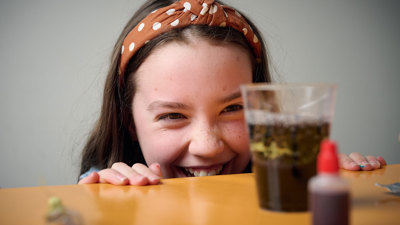 A young adult inspects the liquid in their cup during a Science Studio workshop at Scienceworks.