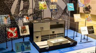 A suitcase full of compartments and various artworks made by immigrants.