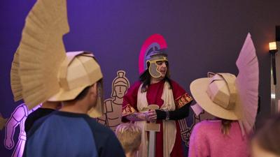 A presenter dressed as a Roman Centurion talks to kids wearing their own Centurion outfits they have made themselves from cardboard.