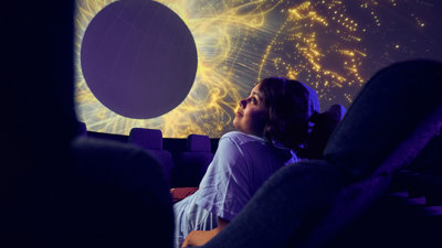A secondary school student observes a projection of the stars on the dome of the Melbourne Planetarium