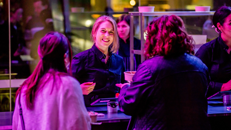 A woman smiles as she hands a order of food to museum goers.